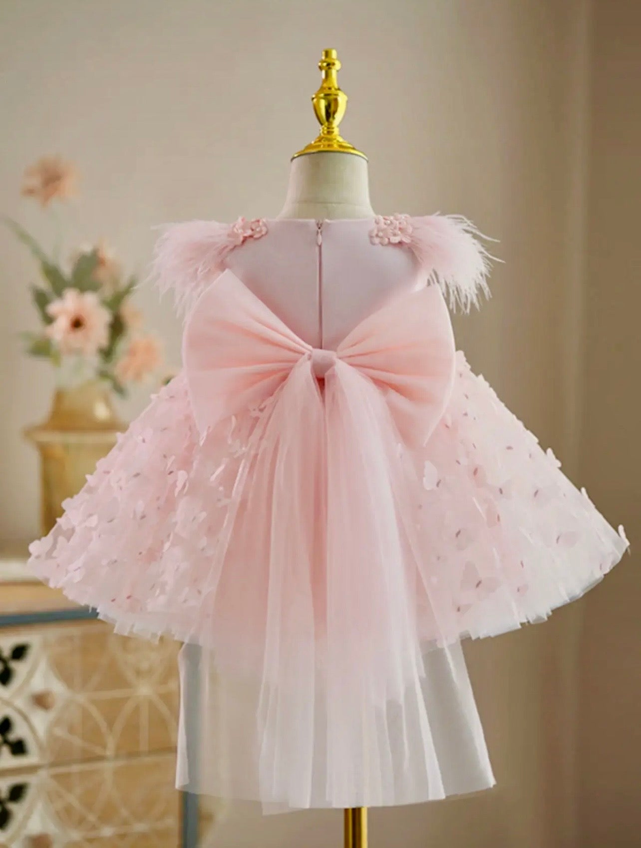 Blush pink baby girl birthday dress with oversized bow and feather shoulders, back view