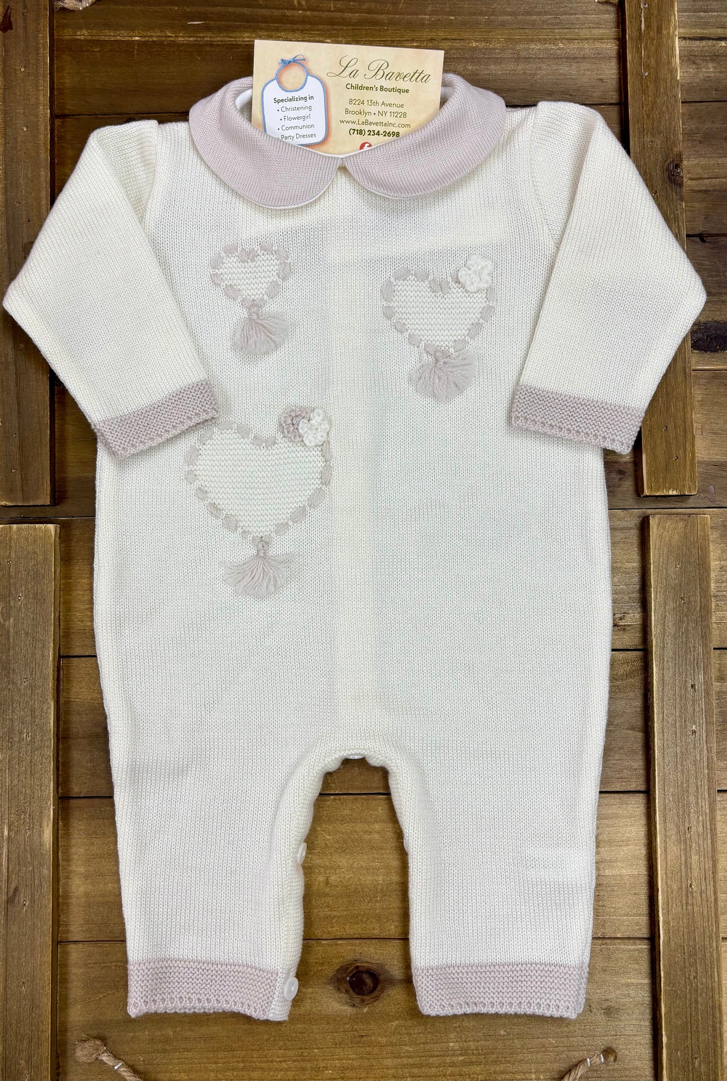Ivory knit baby romper with embroidered lamb motifs and blush pink trim