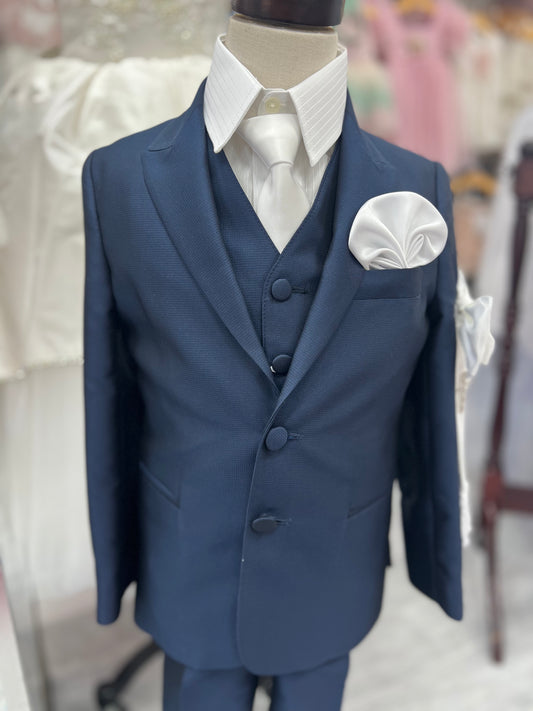 A navy blue textured boys' communion suit consisting of a jacket, vest, and trousers displayed on a mannequin.