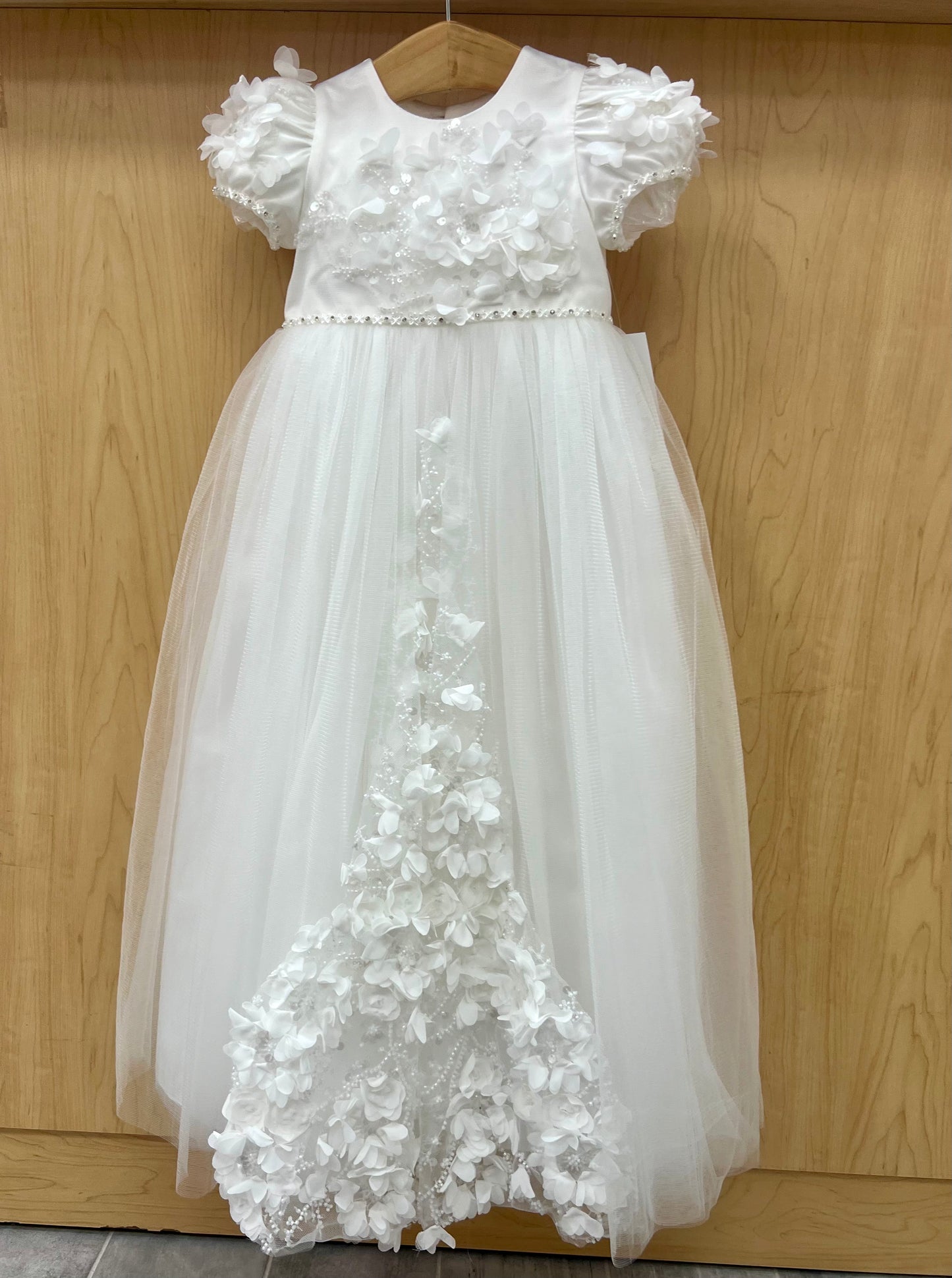 An off white christening dress with 3D floral details and cap sleeves