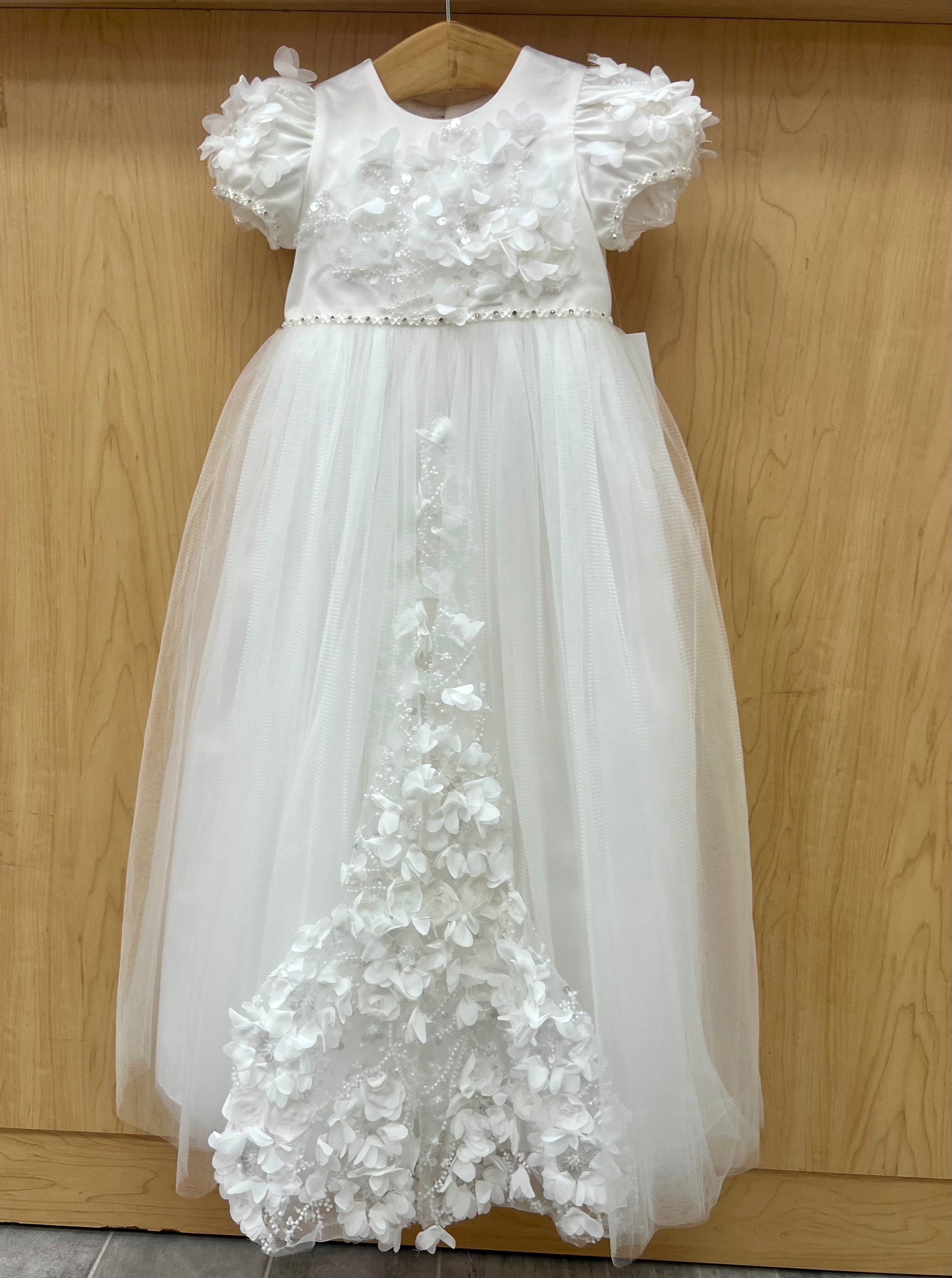 An off white christening dress with 3D floral details and cap sleeves