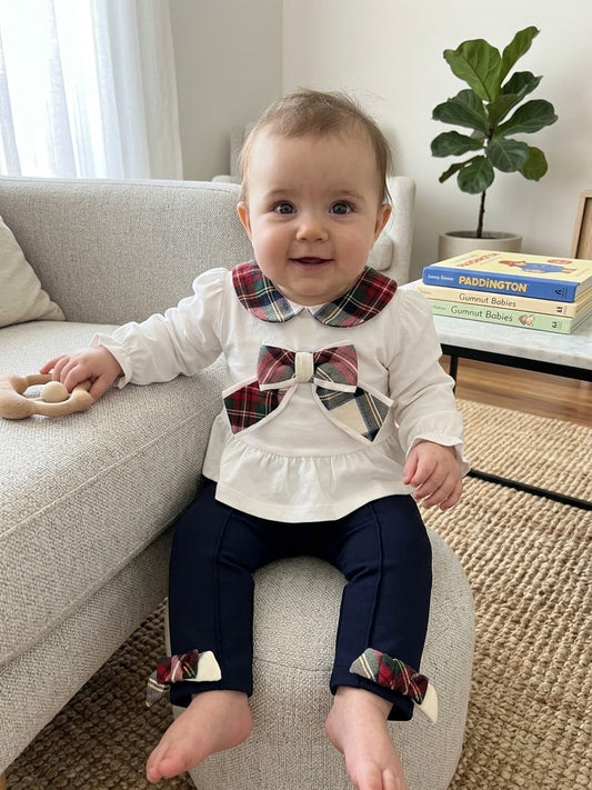 Baby wearing a white long-sleeve top with plaid collar and bow, paired with navy pants with plaid bow cuffs