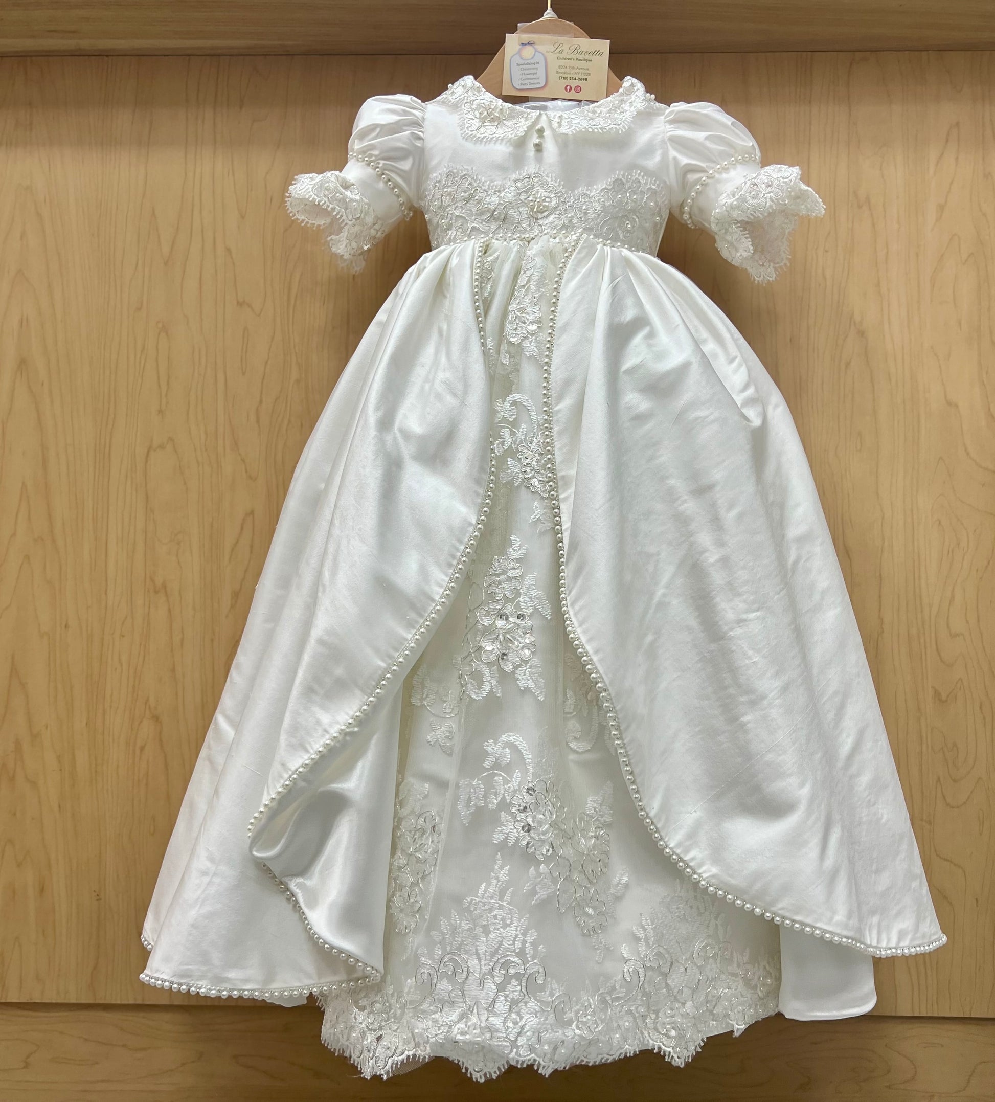Elegant White lace christening dress on a wooden background