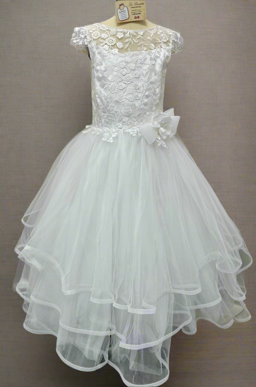 A white, tiered communion dress with cap sleeves and floral embroidery, displayed on a mannequin against a plain background.