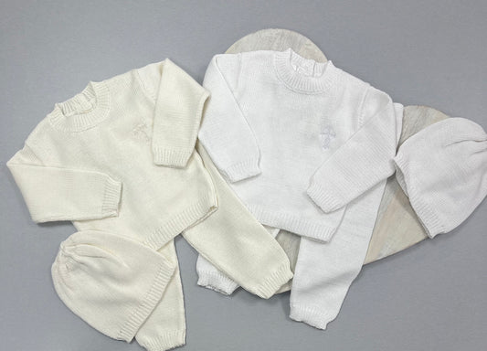 A set of white baby clothes including a long-sleeved top and a beanie hat, displayed on a grey background.
