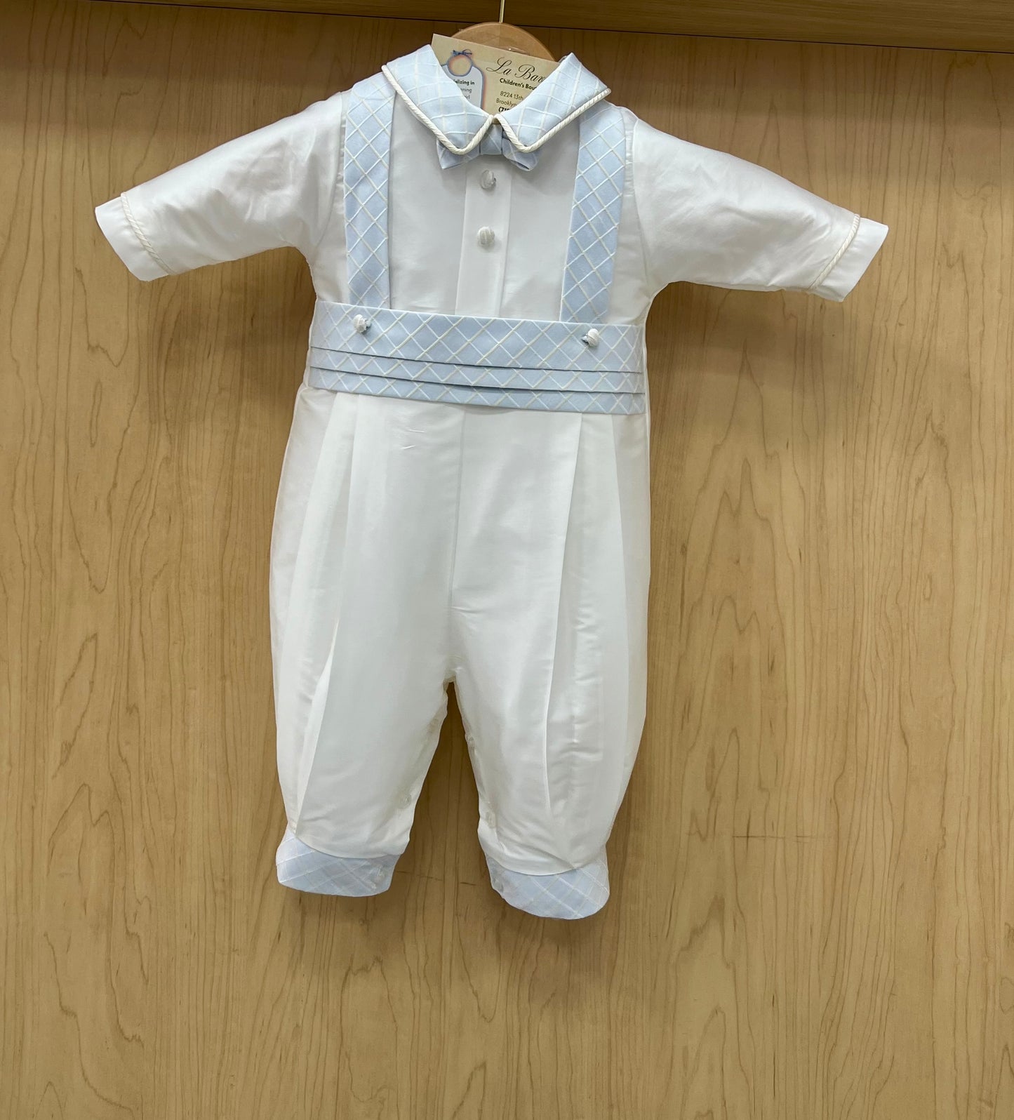 White baby romper with blue accents on a wooden surface