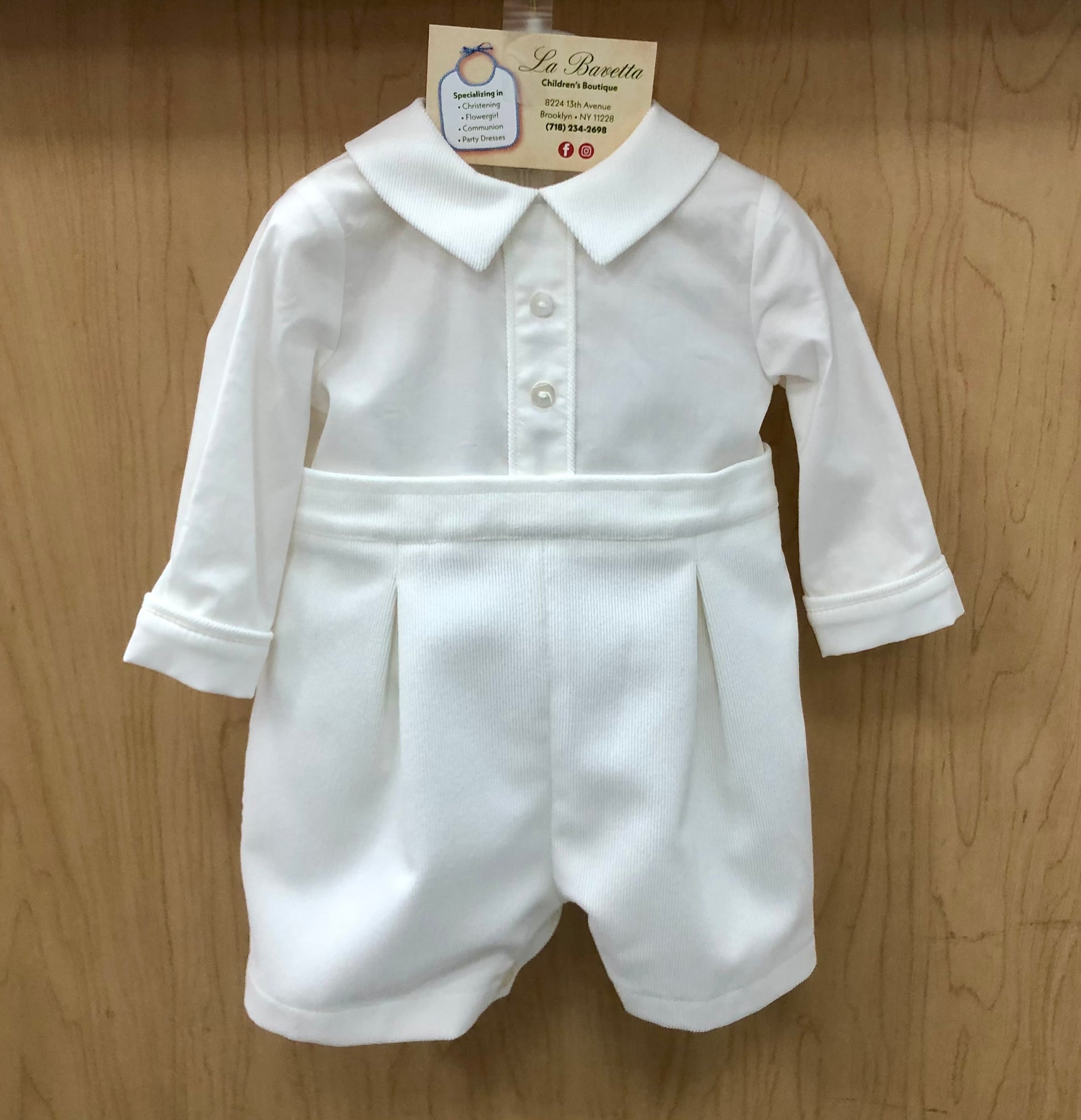 White baby Christening romper with collar on a wooden background